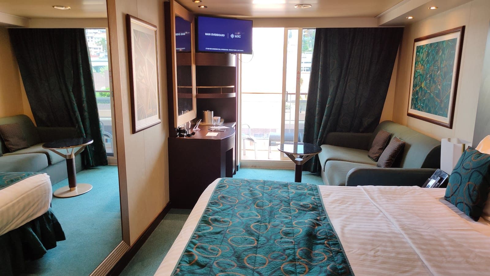 Cruise cabin interior with a bed, desk and balcony door