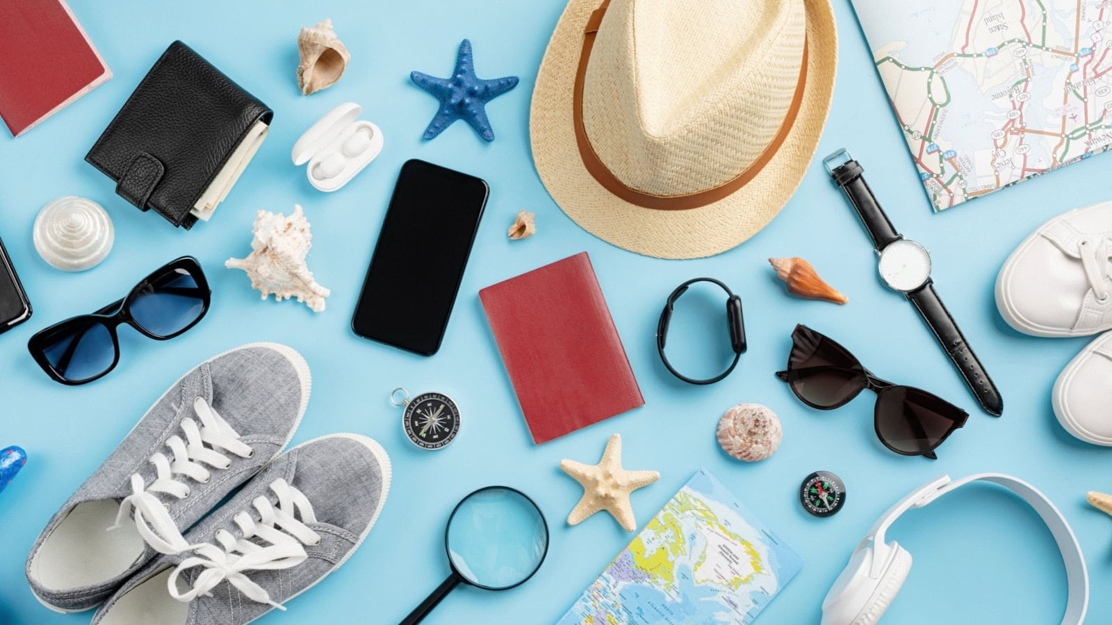 Passport, map, sunglasses and other cruise travel essentials arranged on a blue background
