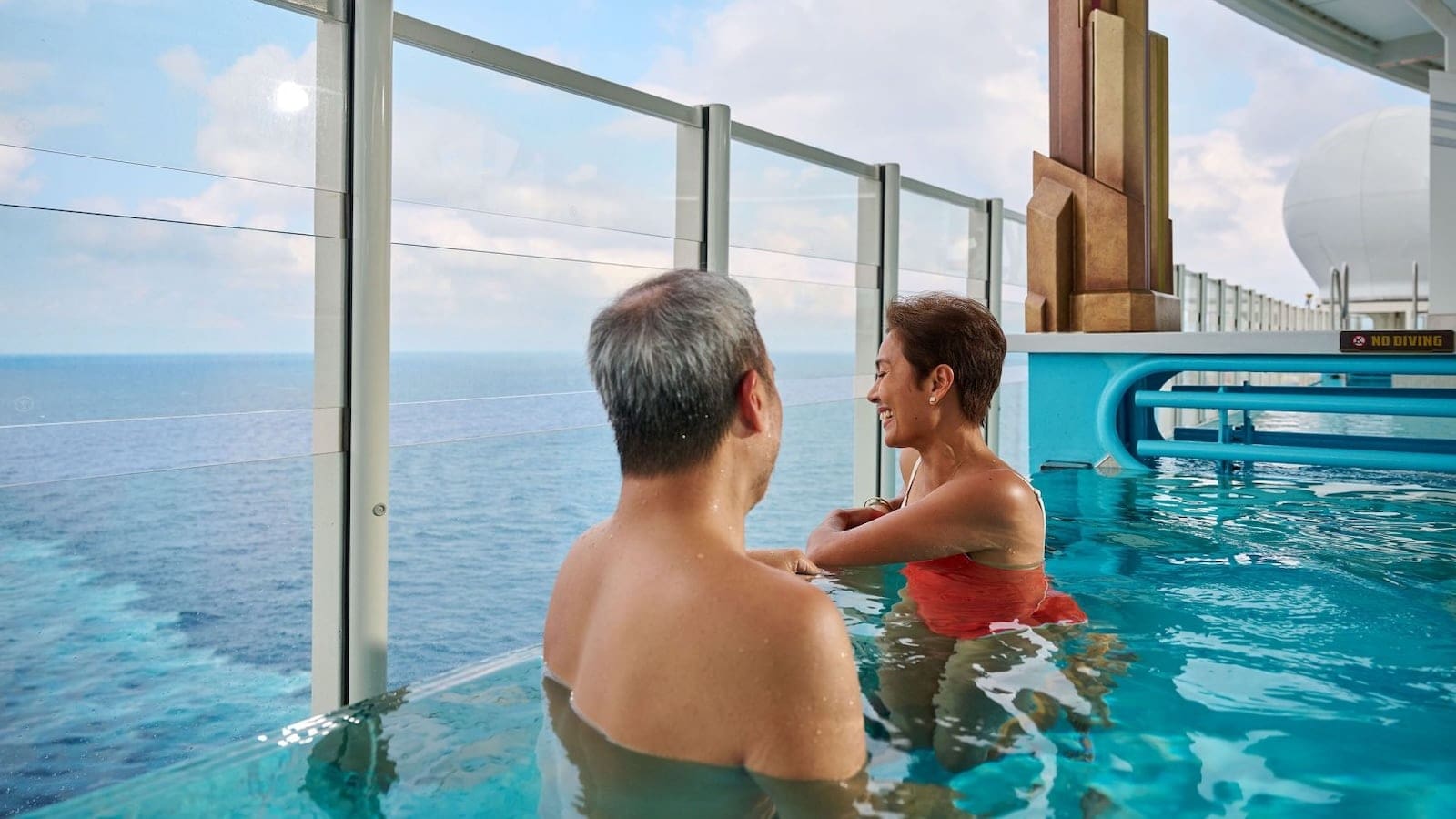 Guests relaxing in the infinity pool on the upper deck of the Disney Adventure cruise ship overlooking the ocean