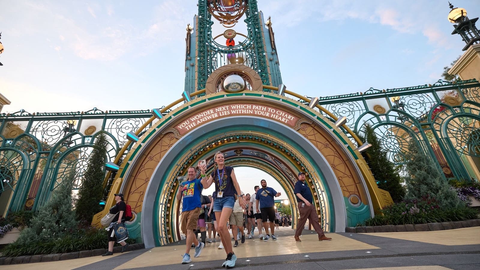 Guests walk beneath the entrance portal at Universal Epic Universe