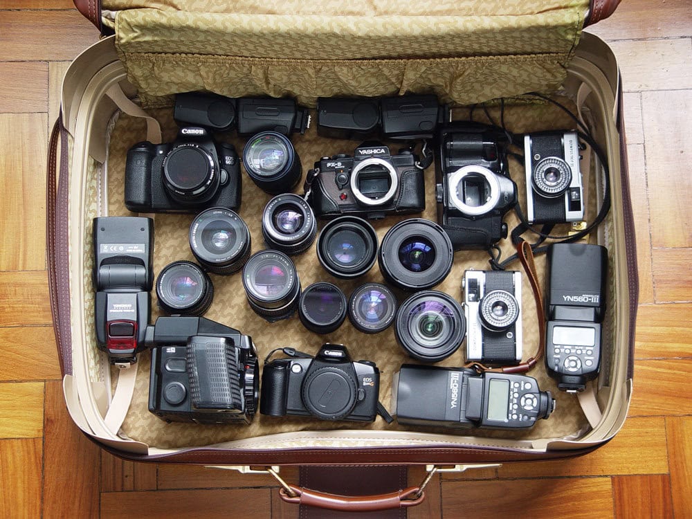 An open hard shell suitcase filled with professional camera equipment, including multiple lenses and camera bodies neatly packed for travel.