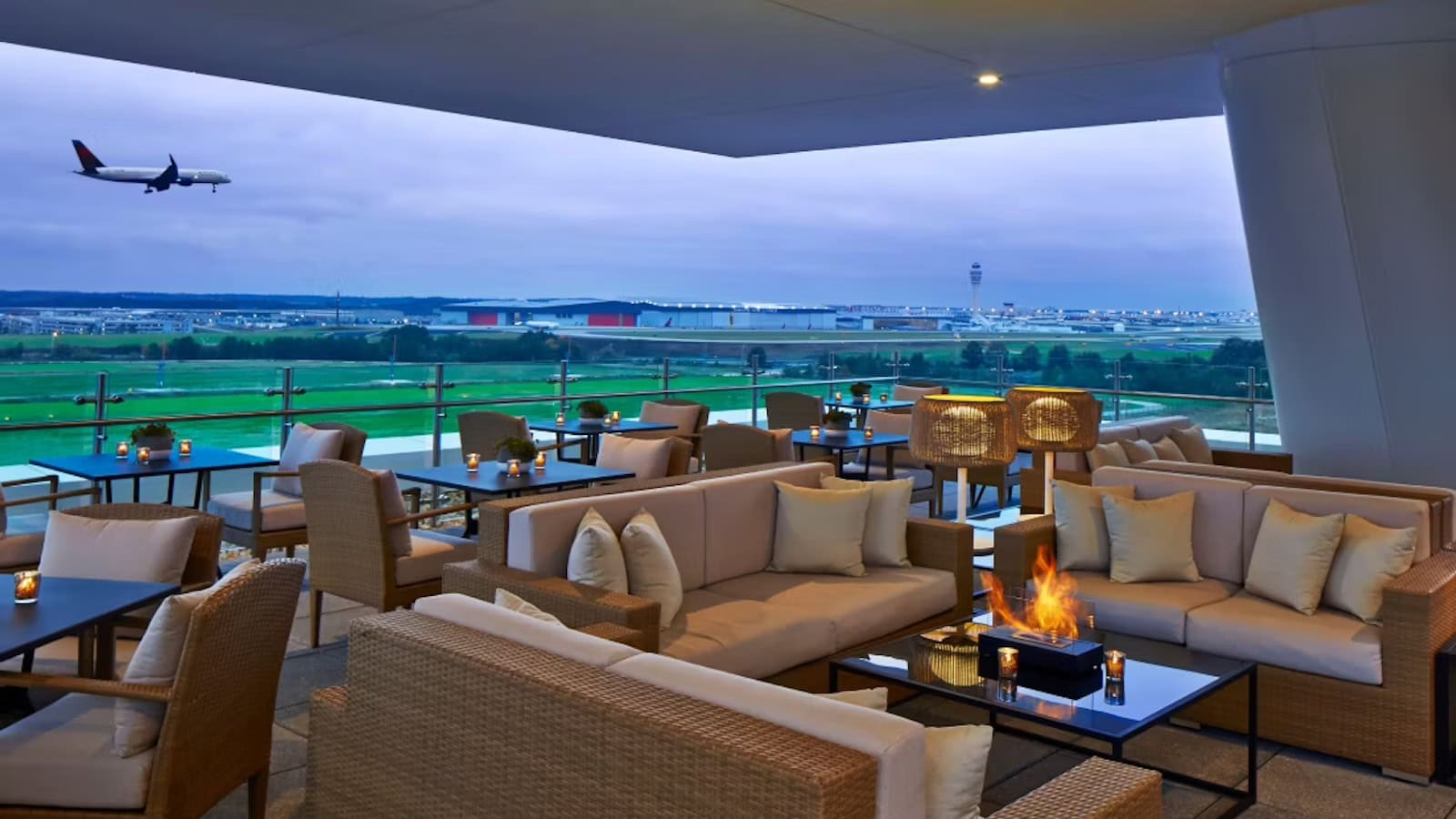 Airport lounge seating overlooking a runway with an aircraft on approach