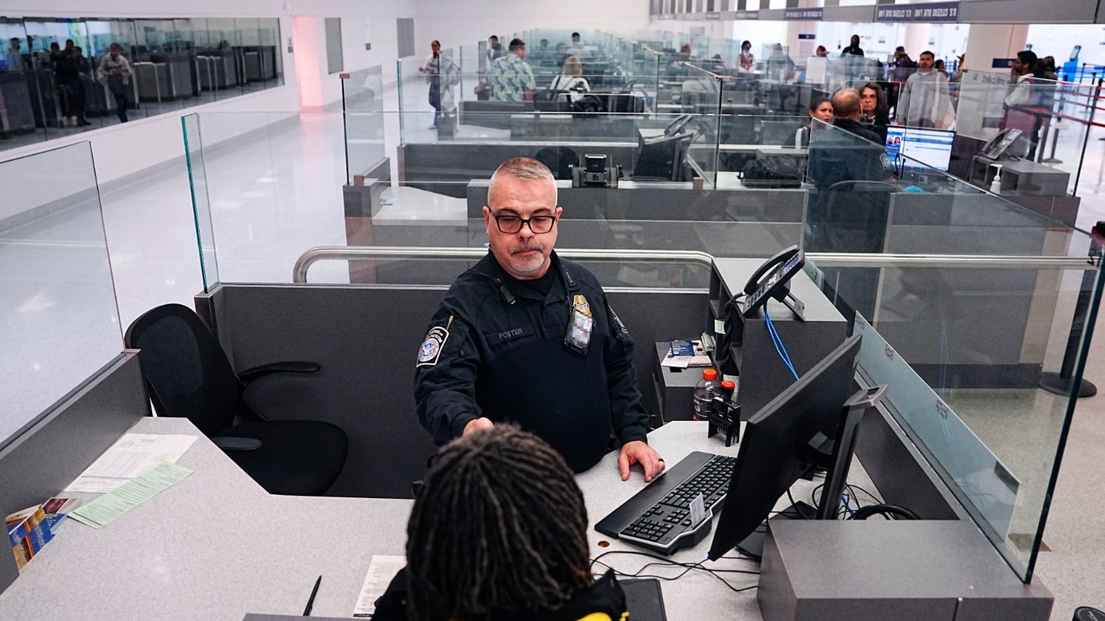 A U.S. Customs and Border Protection officer processes an arriving international traveler at a passport control booth at Baltimore/Washington International Airport