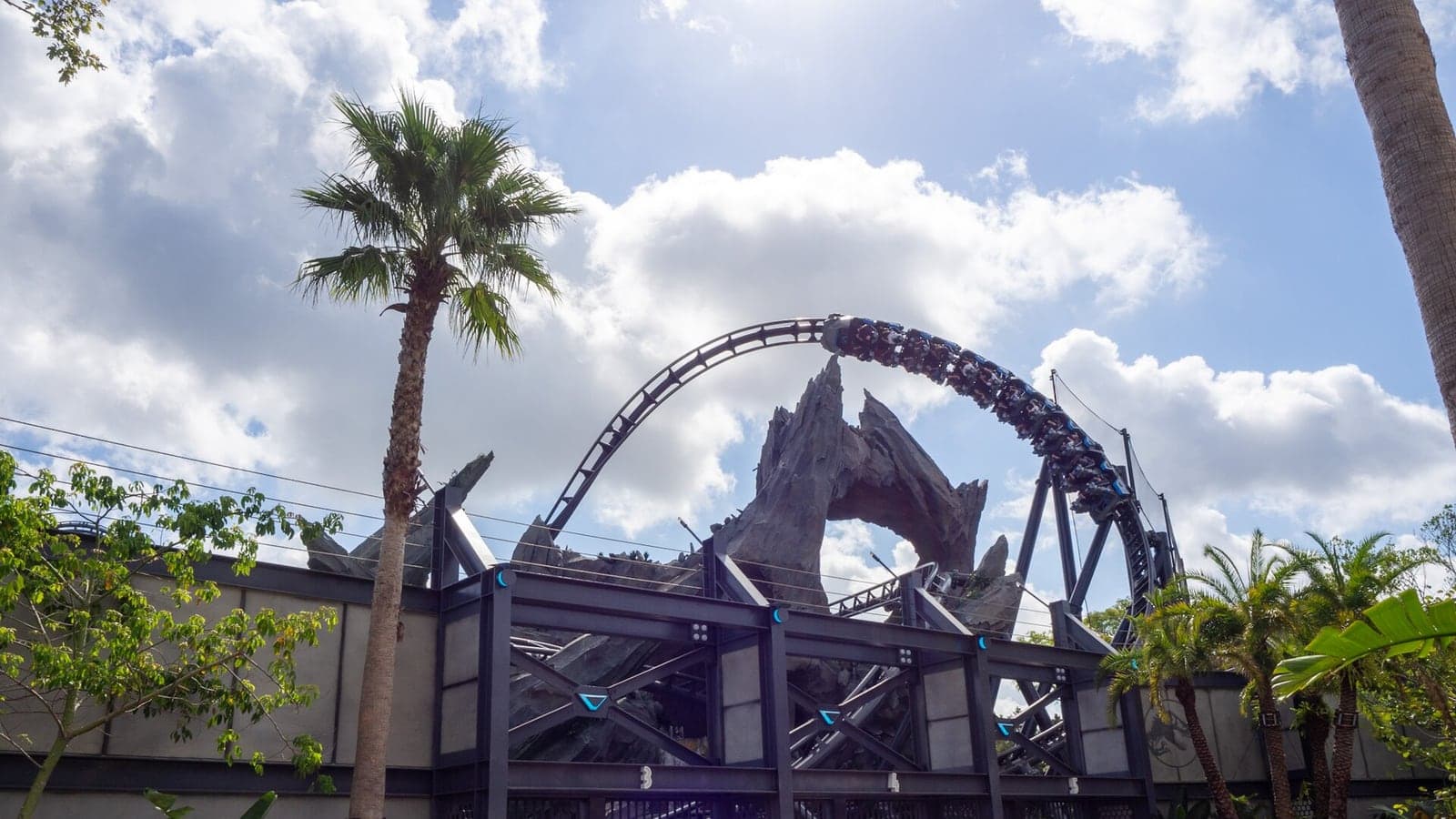 A Jurassic World VelociCoaster train dives through the rockwork at Universal Islands of Adventure.