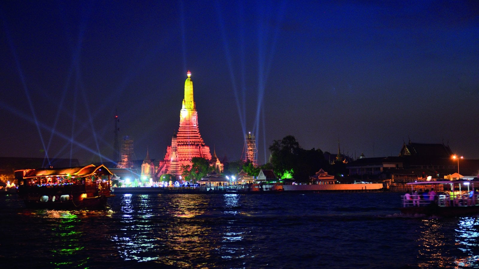 Wat Arun temple lit up at night over the Chao Phraya River in Bangkok, Thailand