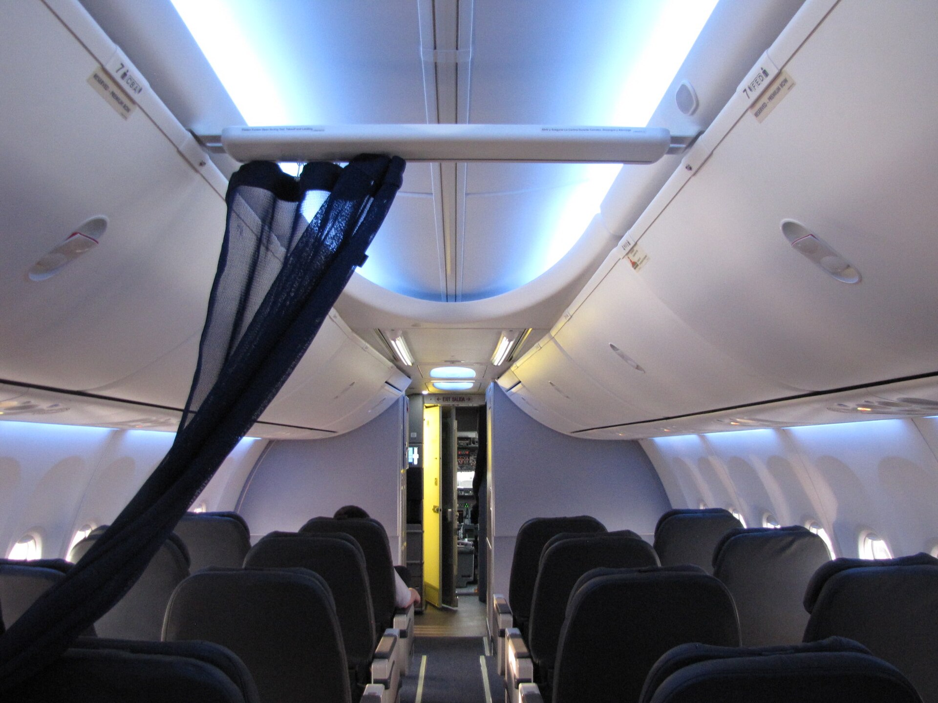 A bright and modern domestic first class narrowbody aircraft cabin featuring spacious leather recliner seats