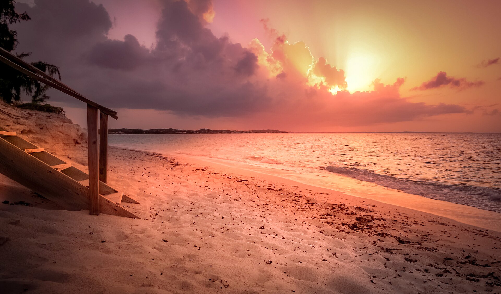 A beautiful sunset view of Grace Bay Beach in Turks and Caicos with calm turquoise waters under a dramatic evening sky.