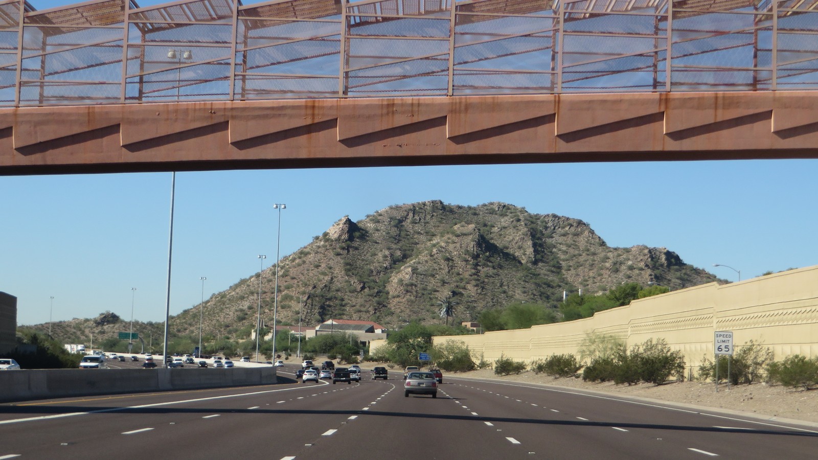 Traffic on Piestewa Freeway SR 51 in Phoenix with desert mountain ahead under a pedestrian bridge