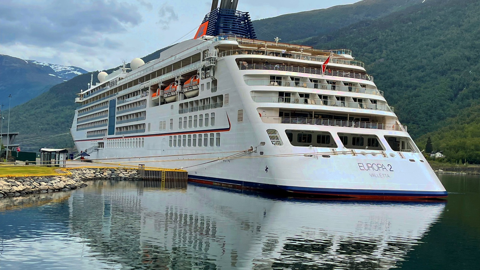 Hapag-Lloyd Cruises EUROPA 2 docked beside a mountain landscape