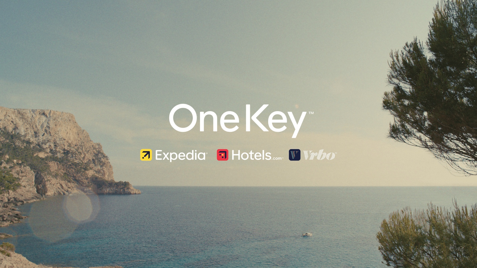 One Key loyalty program branding for Expedia, Hotels.com and Vrbo over a coastal travel scene