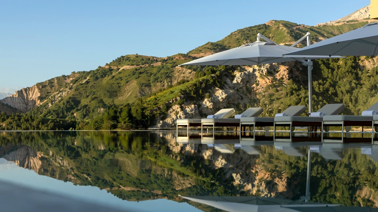 Infinity pool and lounge chairs overlooking green mountains at Beldersoy Resort and SPA