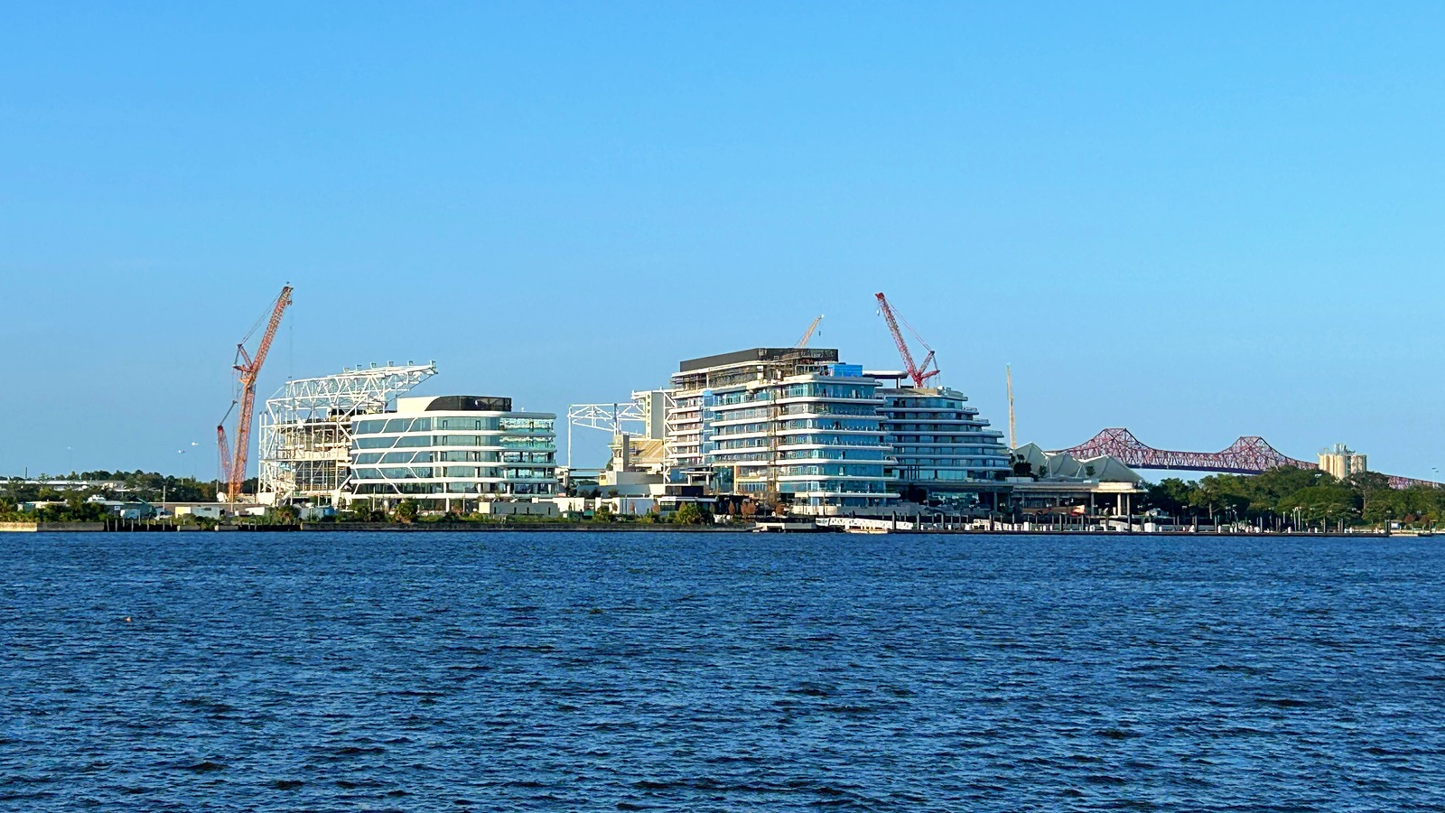 Waterfront hotel towers under construction with cranes along a US shoreline