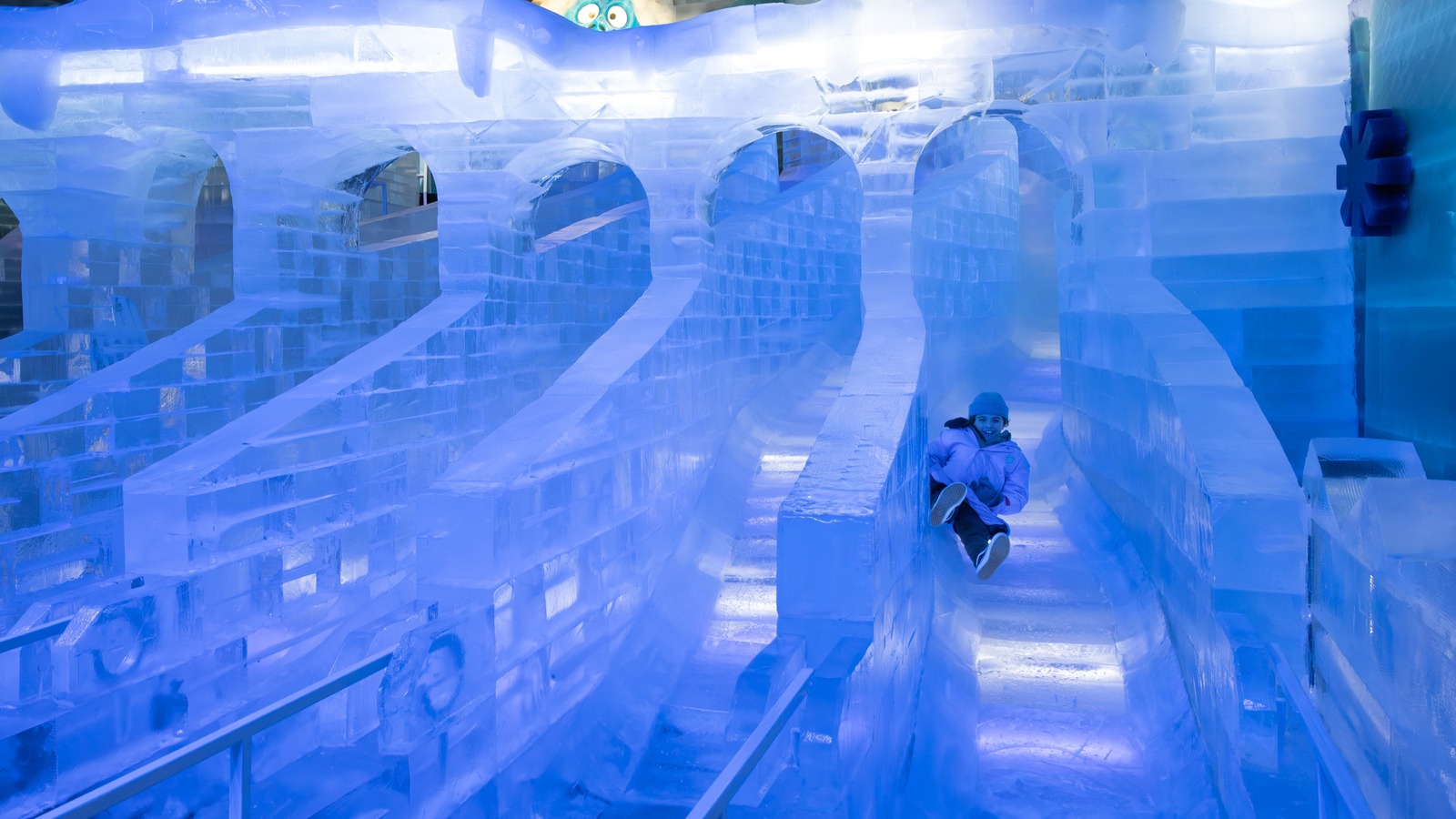 Guests in blue parkas viewing Home Alone themed ice sculptures at a Gaylord ice attraction