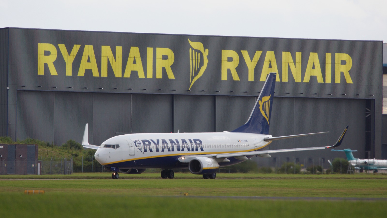 Ryanair Boeing 737-800 EI-DAK taxiing past a Ryanair hangar with yellow branding