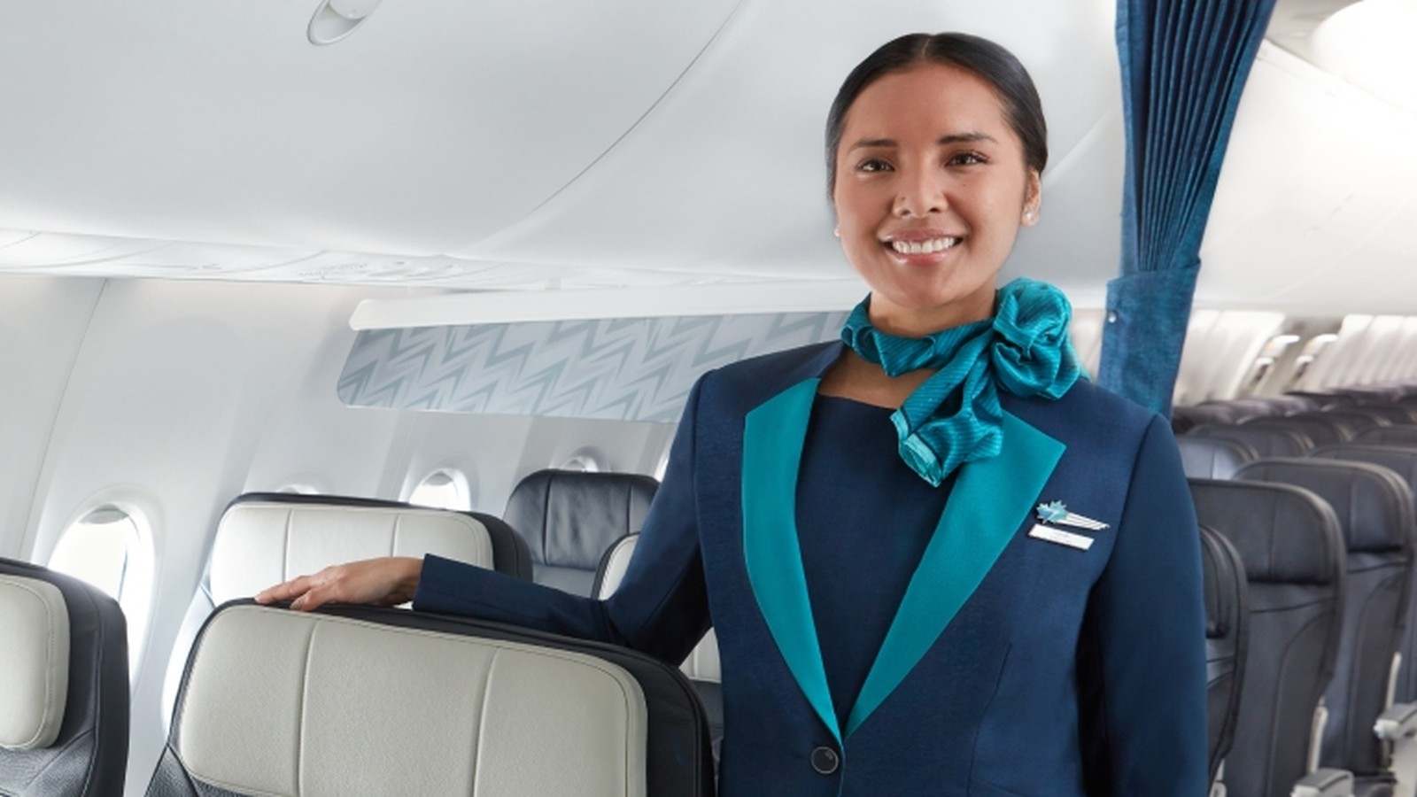 WestJet cabin crew member in uniform standing in an aircraft cabin aisle