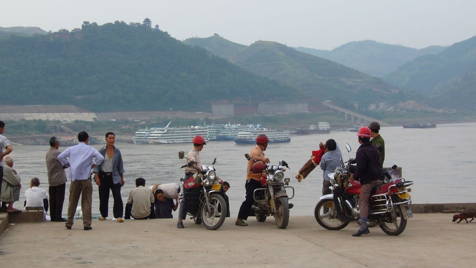 Multiple multi-deck cruise vessels underway on the Yangtze River under partly cloudy sky