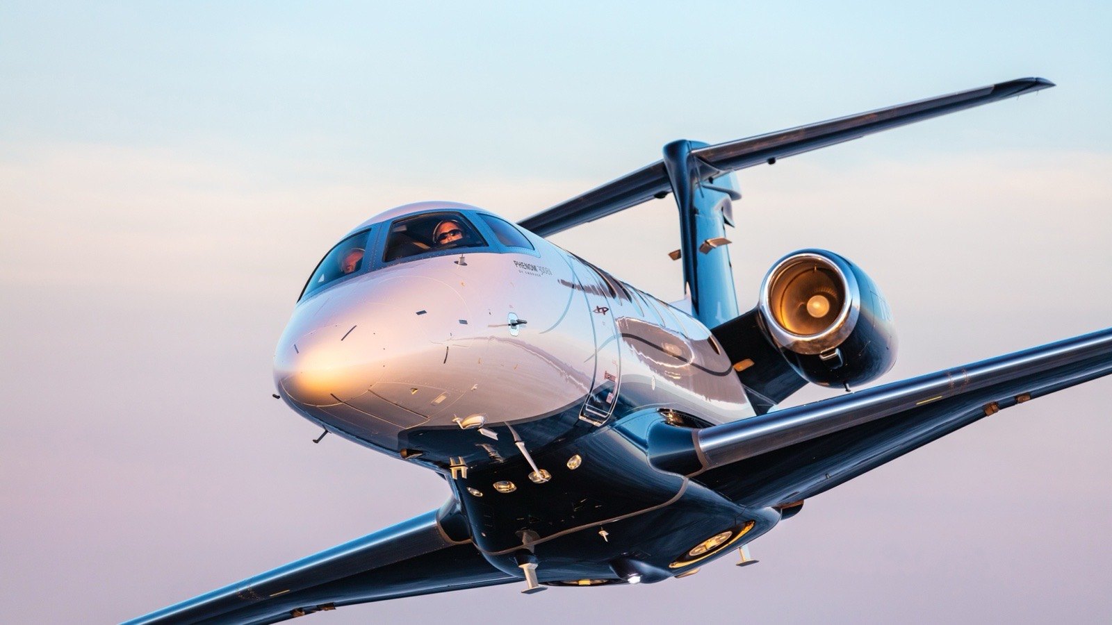 Embraer Phenom 300EV business jet flying against a bright sky