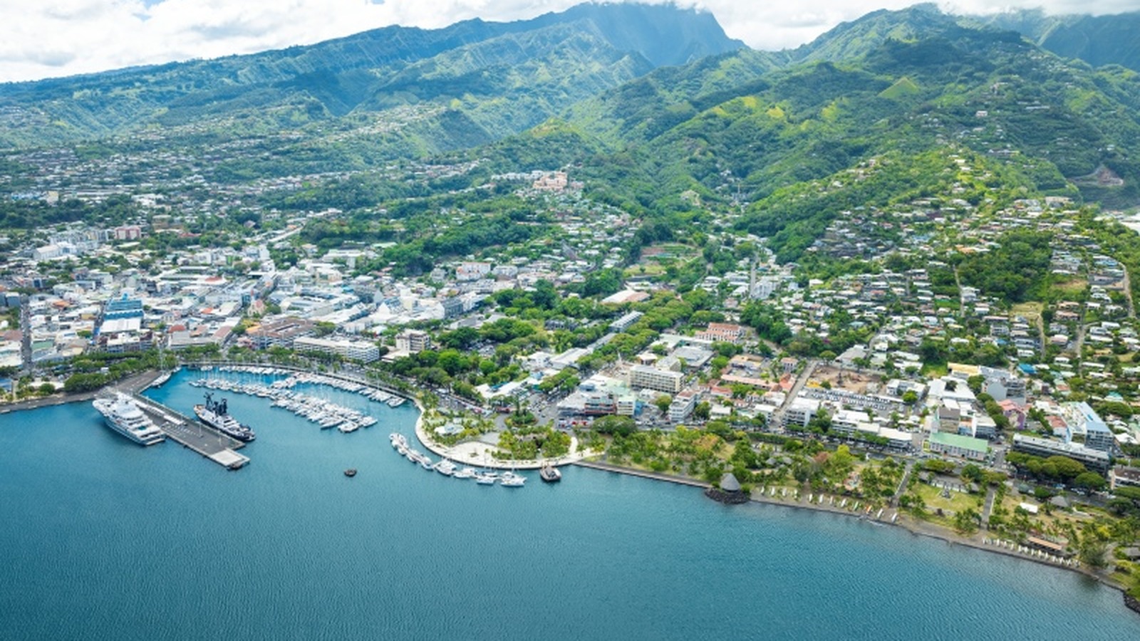 Aerial view of Papeete harbor and waterfront with ships docked against green mountains