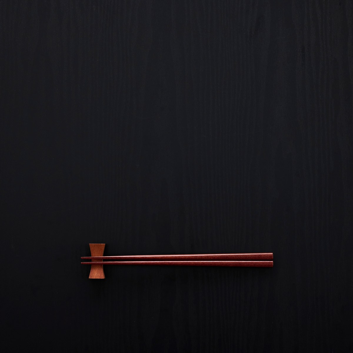 Pair of wooden chopsticks on a dark surface