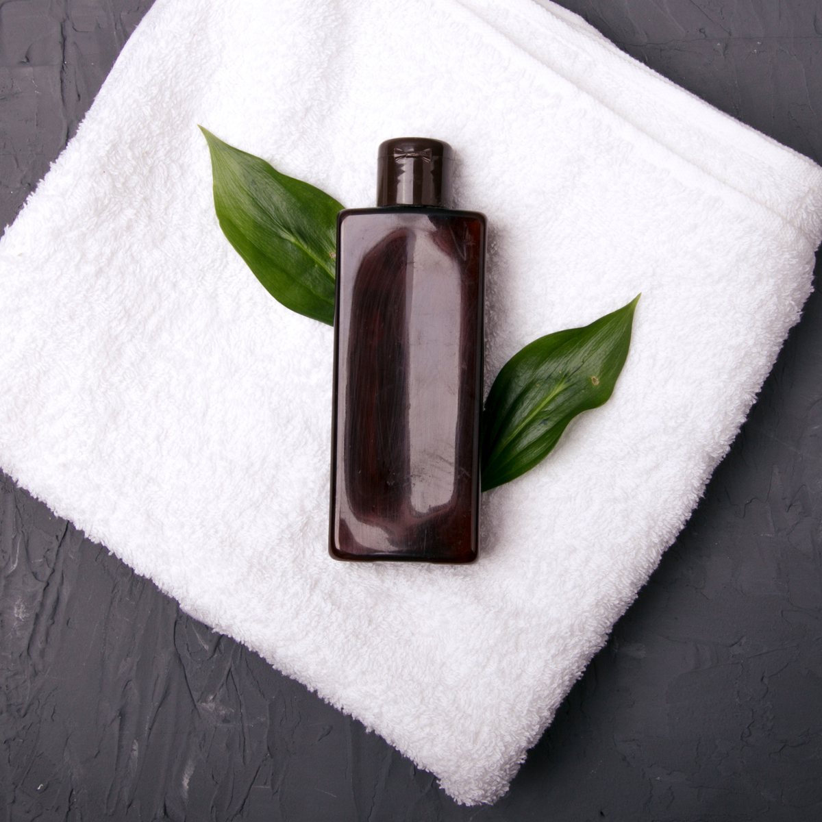 Shampoo bottle on a white towel with green leaves