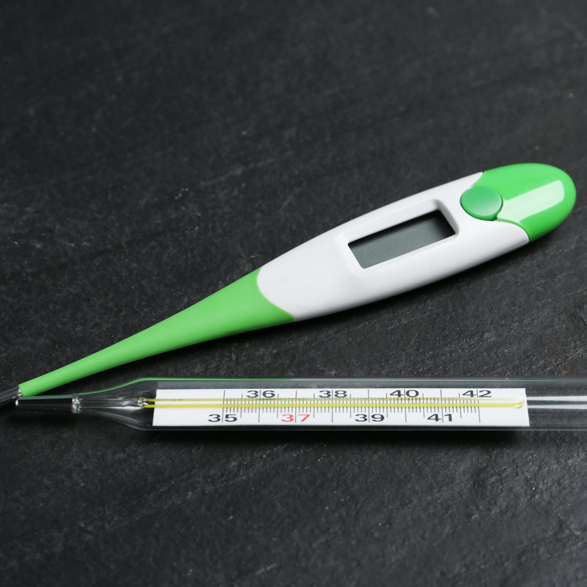 Digital and glass thermometers on a light background