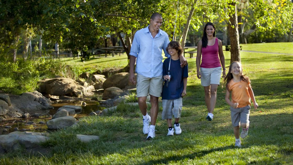 Family walking beside a stream at Yorba Regional Park