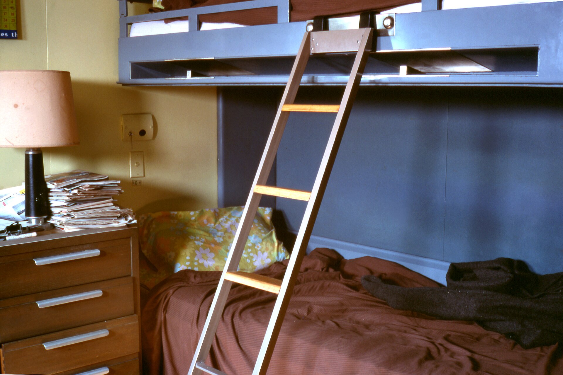 A classic metal pullman bed lowered down from a cabin wall with an access ladder.