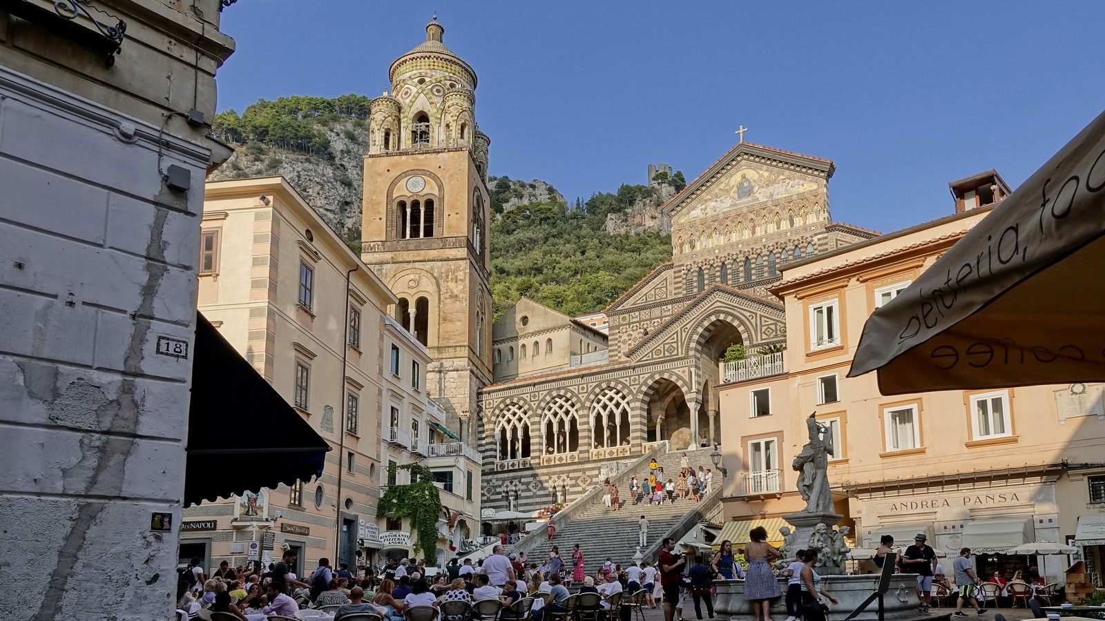 The striped facade and bell tower of the Cathedral of Sant'Andrea above the staircase on Piazza Duomo in Amalfi, Italy