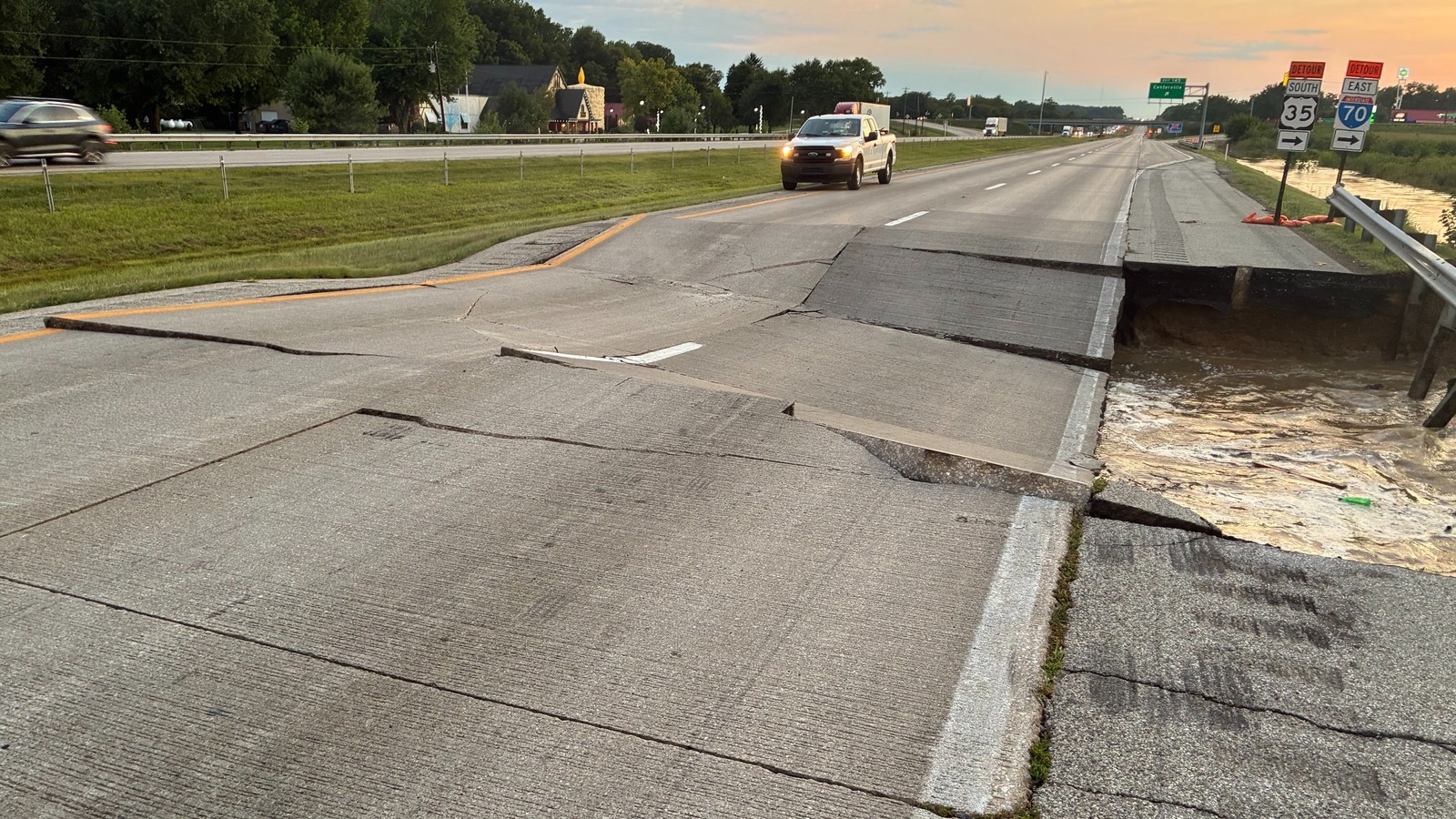 Washed-out westbound Interstate 70 pavement near Centerville with an east 70 detour shield beside floodwater