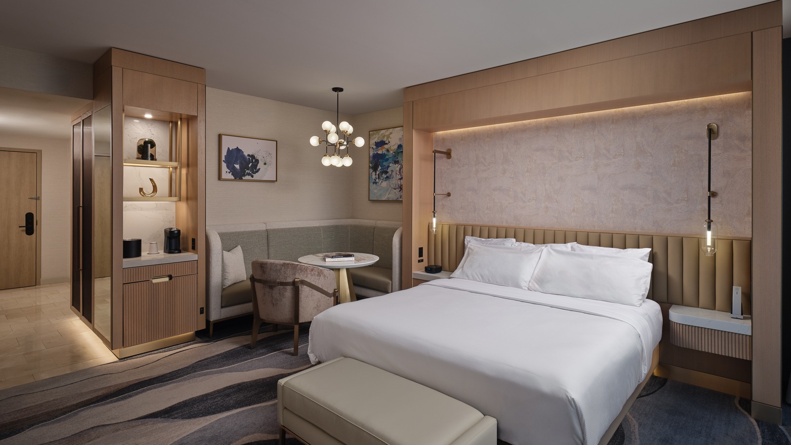 Renovated MotorCity Casino Hotel guestroom configured as a mini suite with seating and Detroit skyline window light