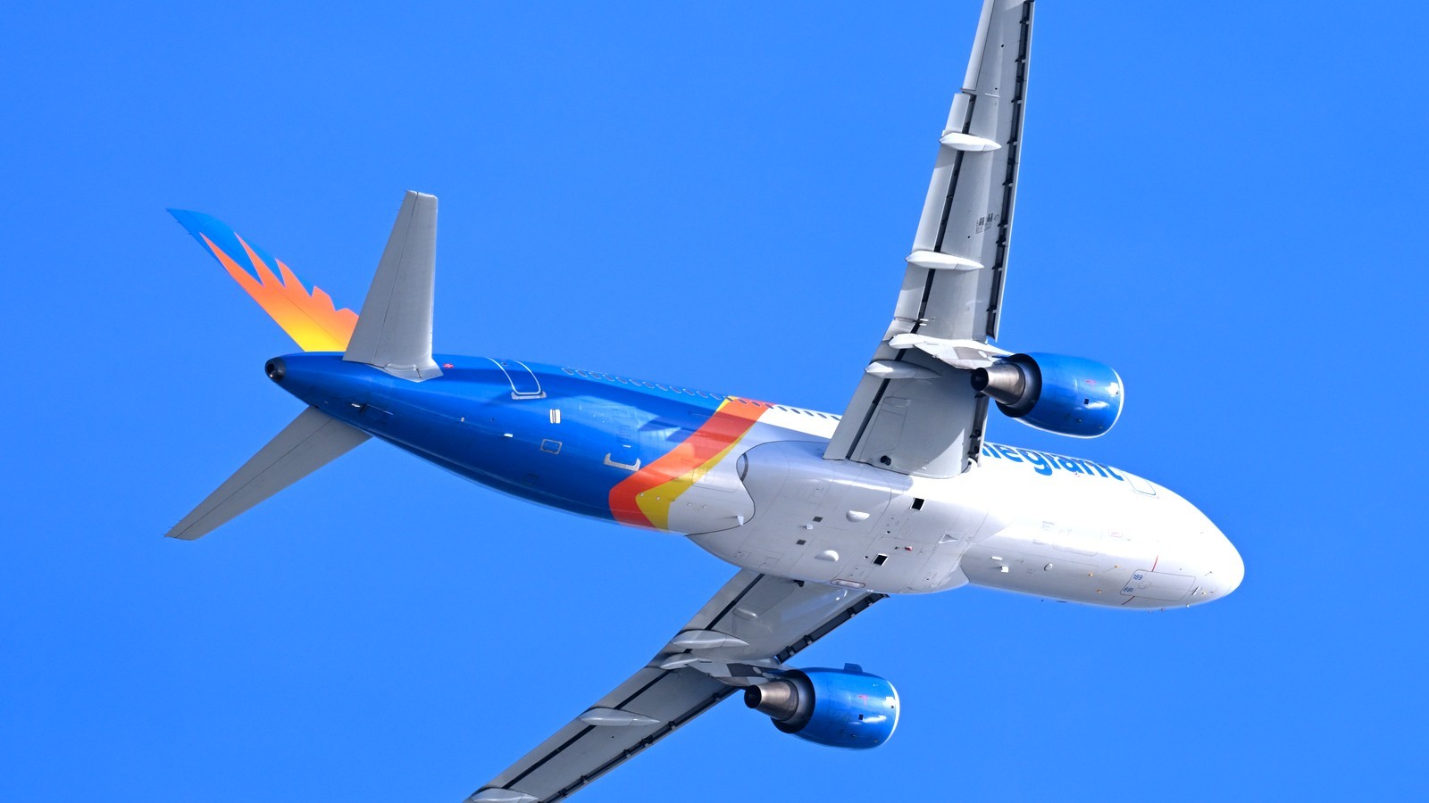 Allegiant Air Airbus A320 in blue and orange livery climbing against a clear blue sky