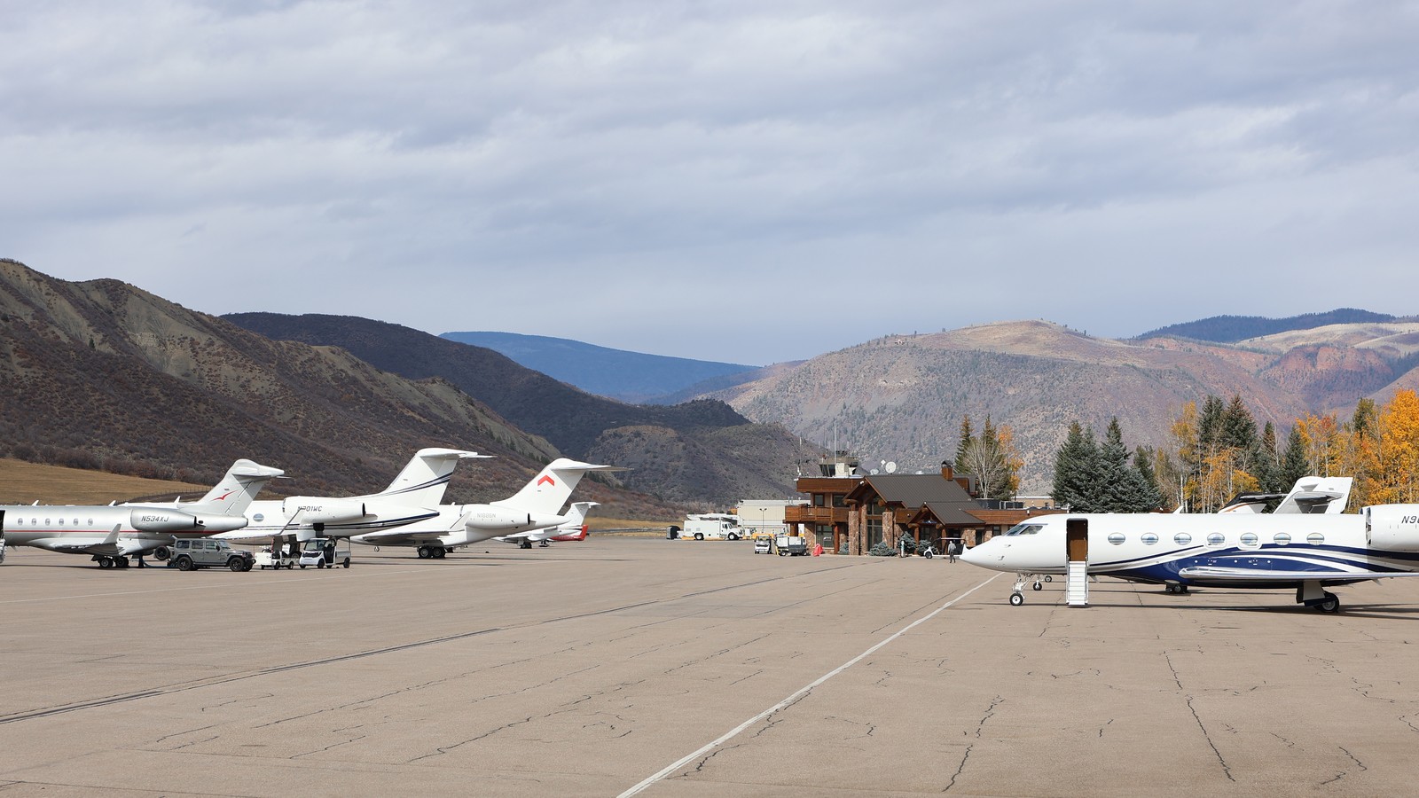 Aircraft parked on the apron at Aspen/Pitkin County Airport with mountains behind