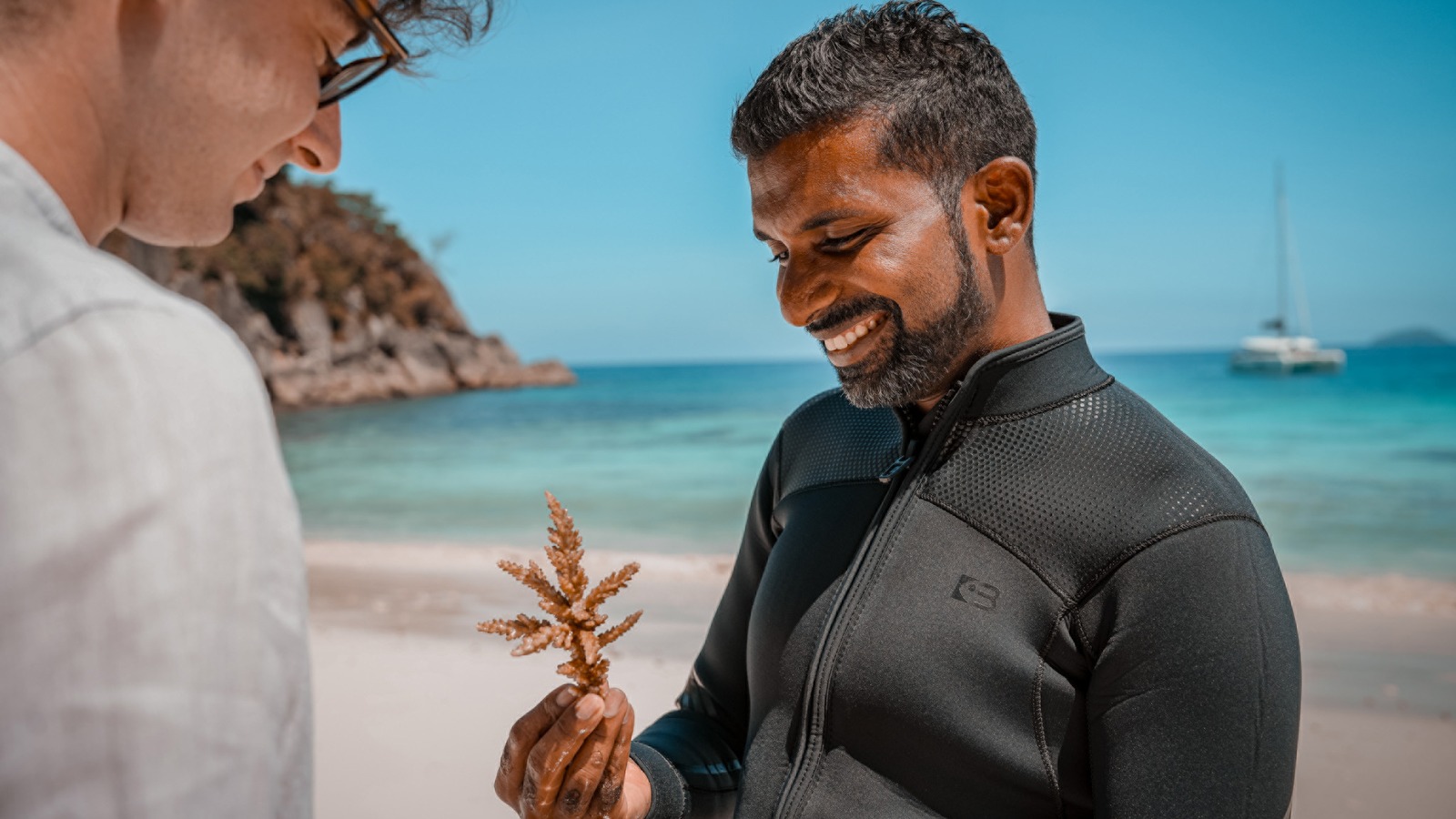 Marine biologist showing a coral fragment to a guest on the beach at Four Seasons Resort Seychelles