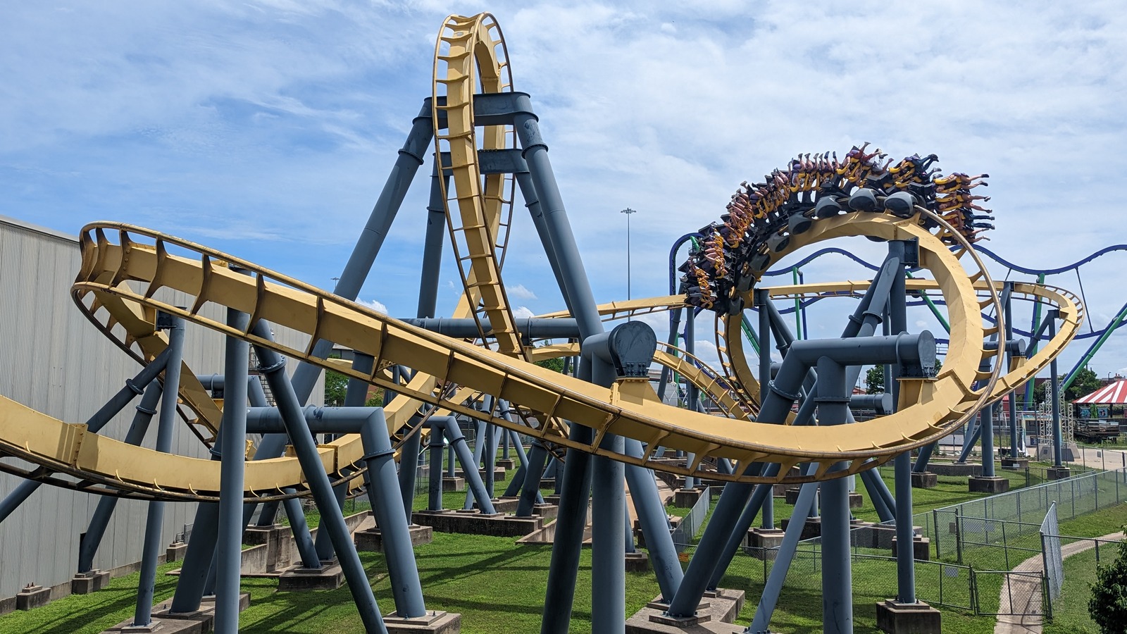 Yellow Batman The Ride inverted coaster train looping at Six Flags Over Texas under blue sky