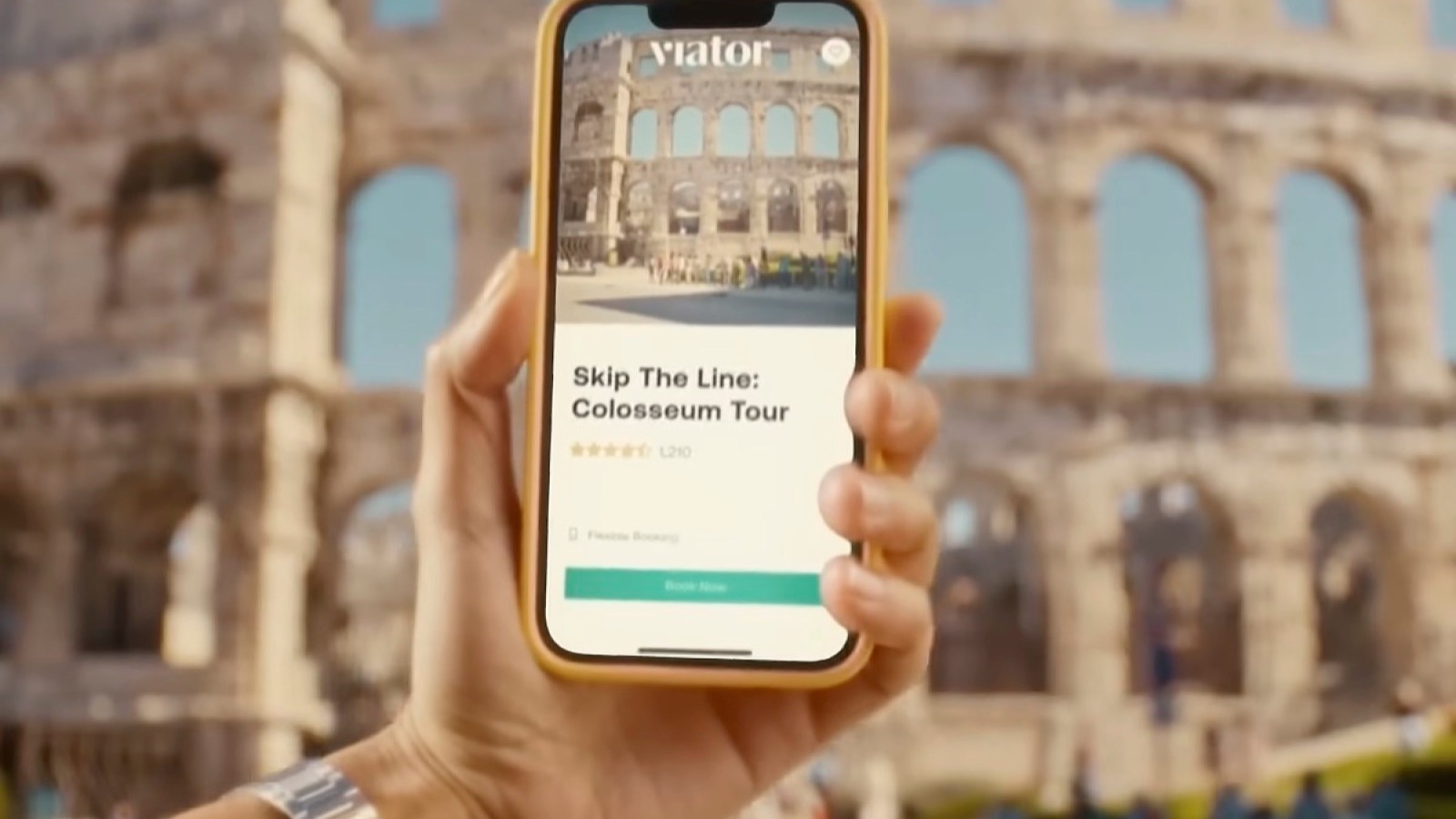 Traveler holding the Viator app in front of the Colosseum while viewing a tour listing