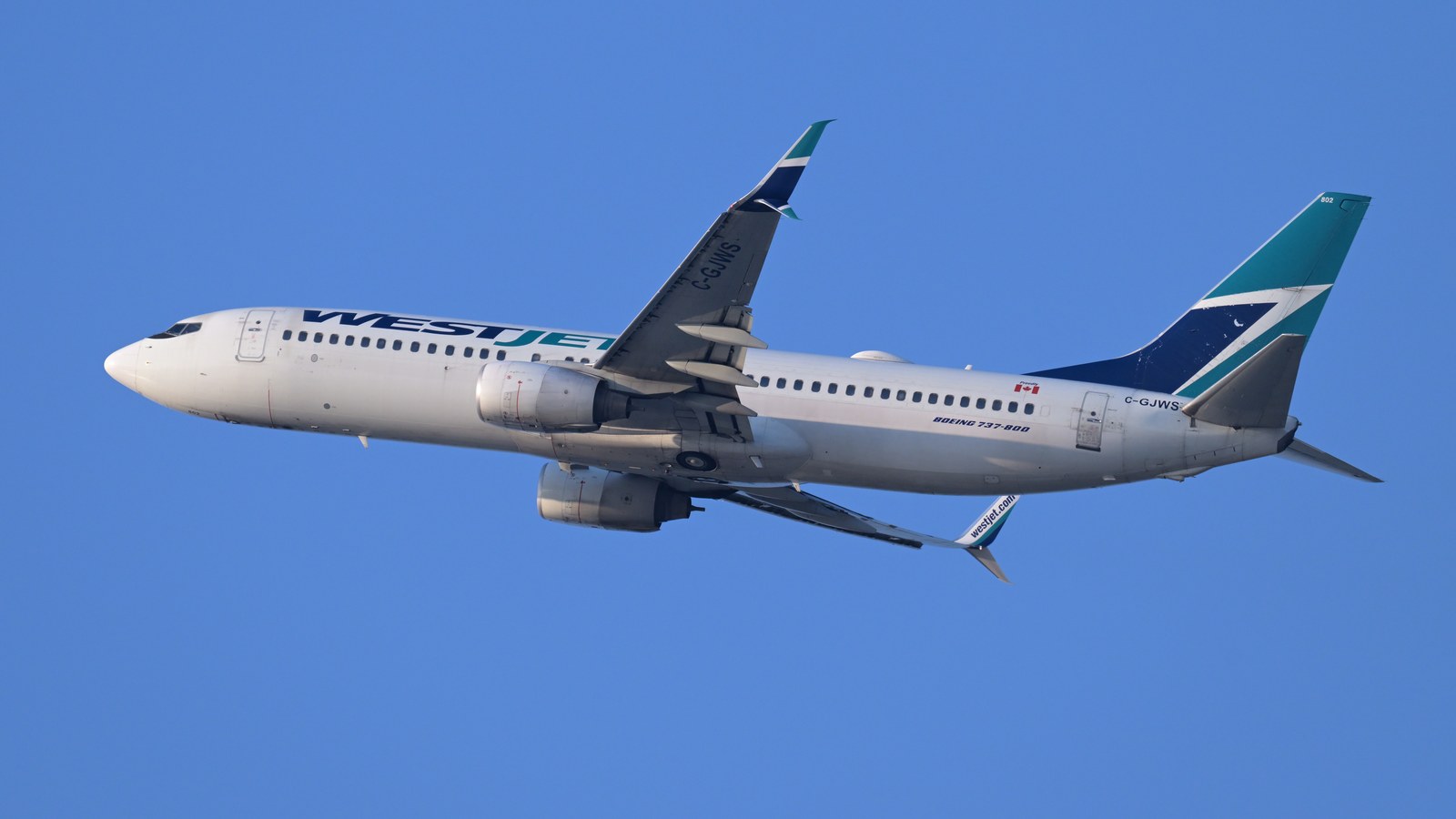 WestJet Boeing 737-800 climbing after departure against a clear blue sky
