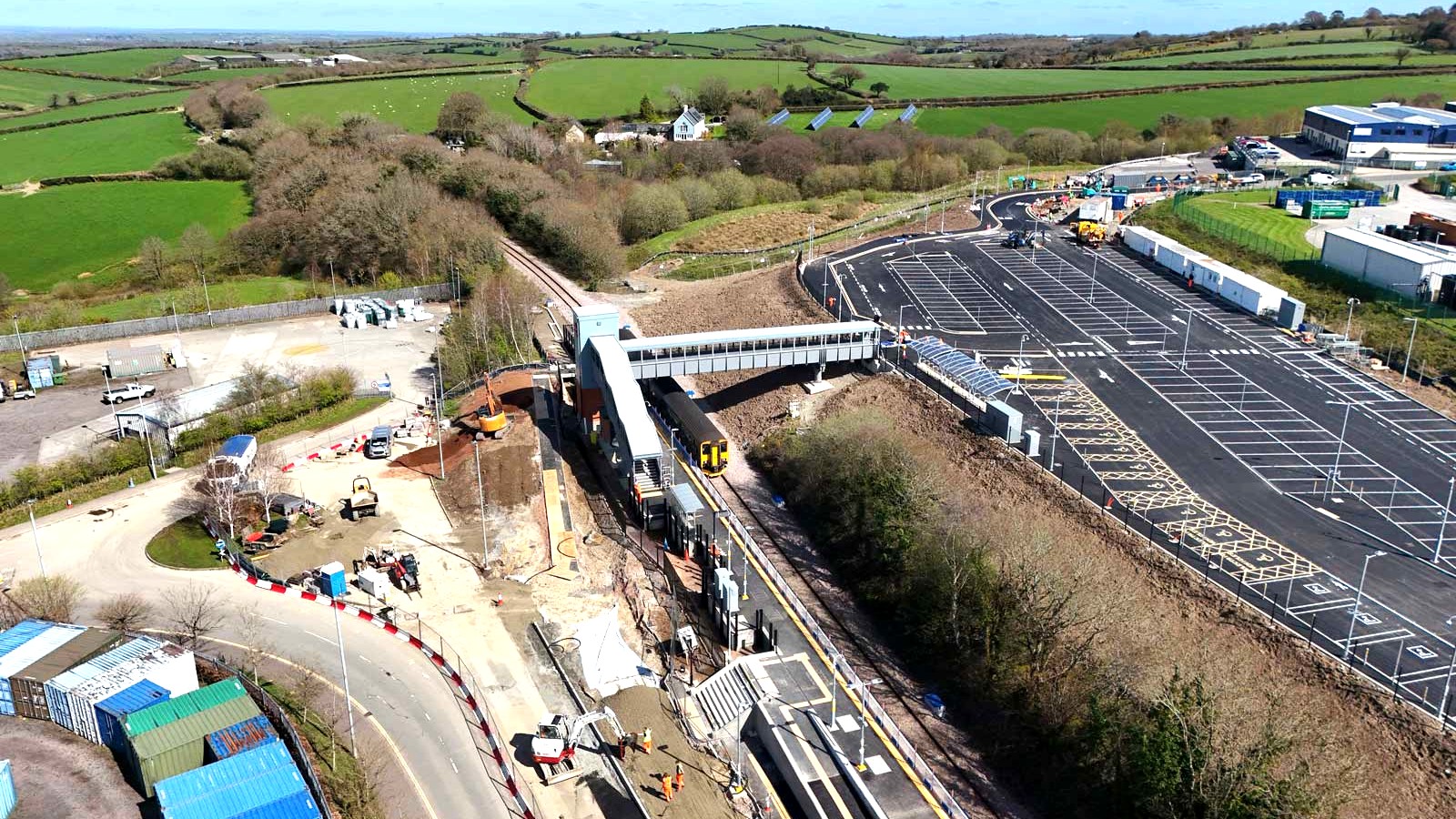 Aerial view of Okehampton Interchange station platform, footbridge, train and car park on the Dartmoor Line