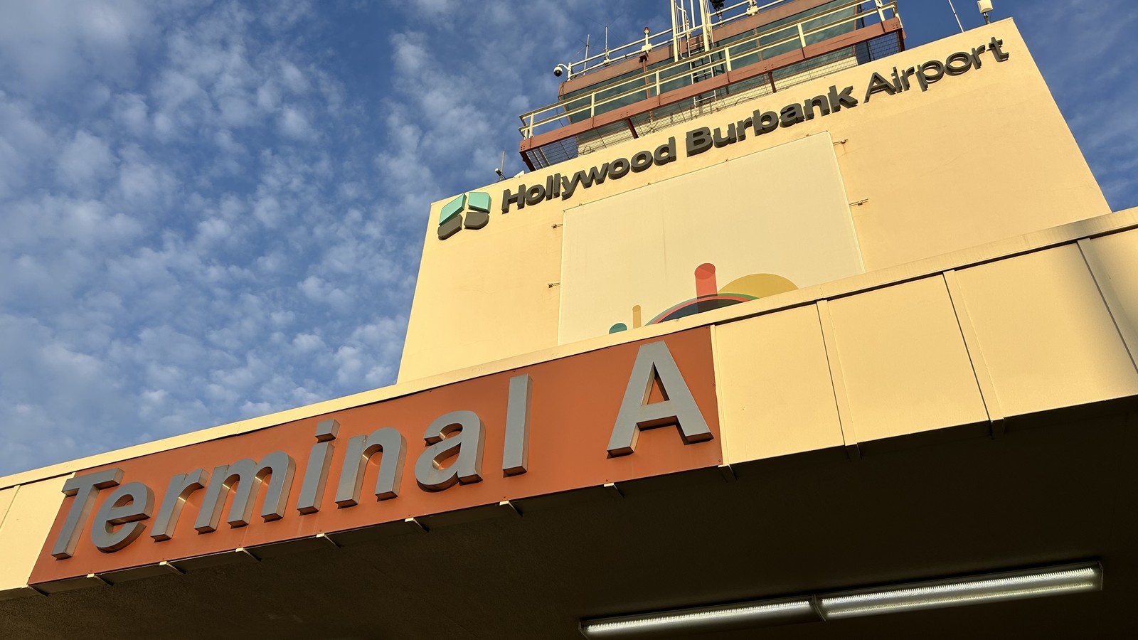 Hollywood Burbank Airport Terminal A exterior signage and control tower under a blue sky