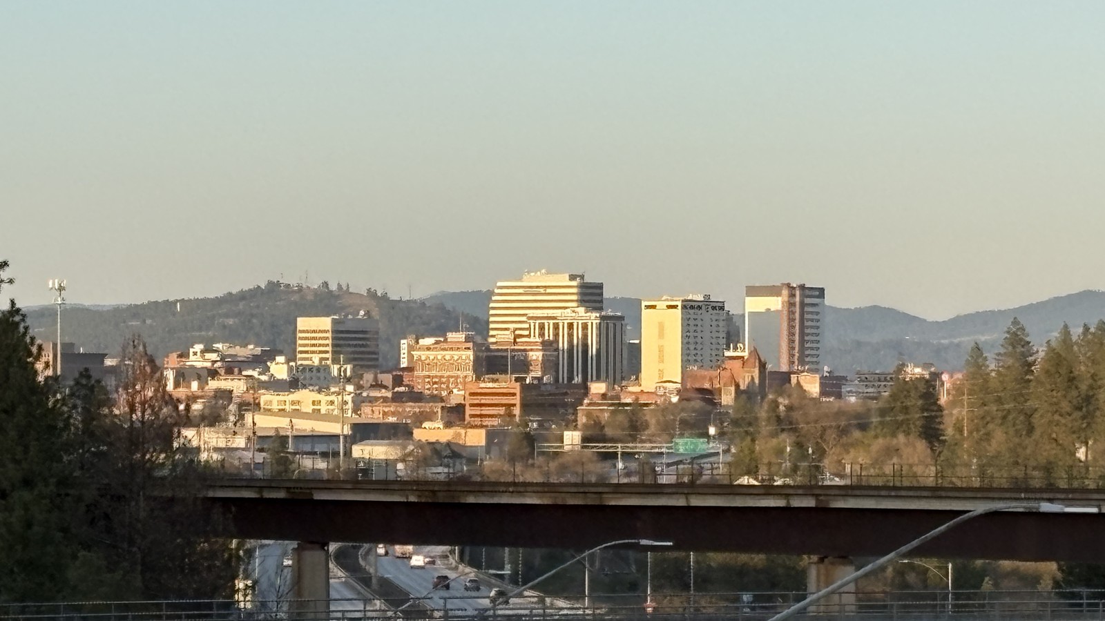 Downtown Spokane Washington skyline and hillside trees under clear light