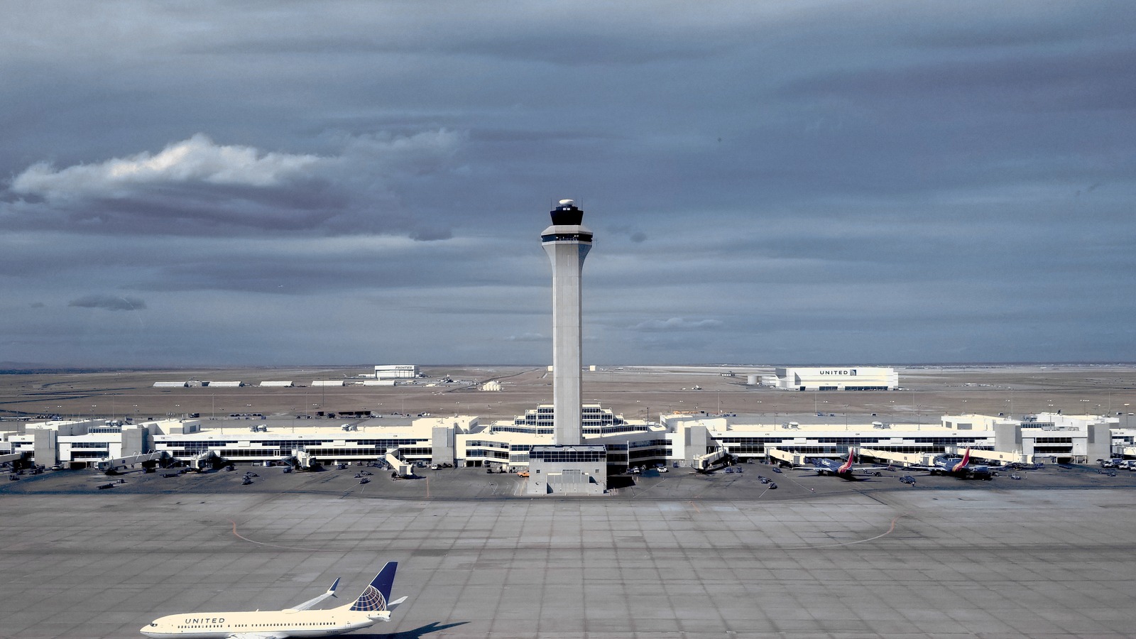 Air traffic control tower at Denver International Airport with a United Airlines jet below