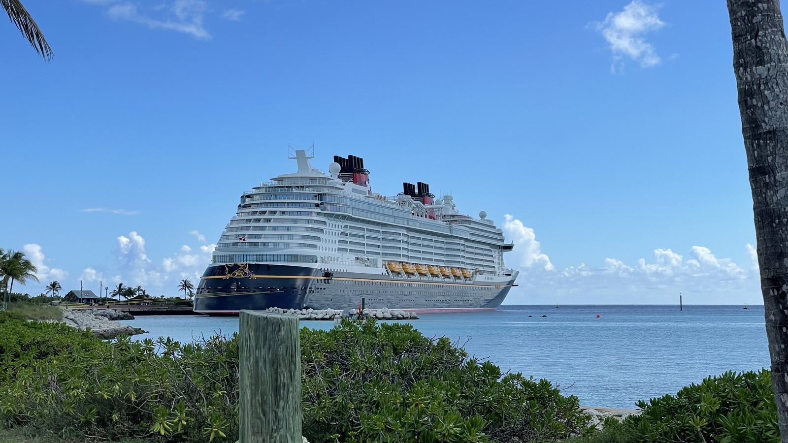 Disney Wish cruise ship at Castaway Cay with yellow hull accents and red Disney funnels