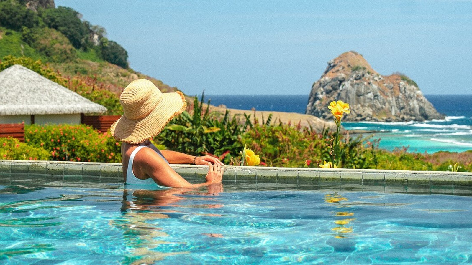 Guest at a Preferred Hotels coastal resort pool overlooking the ocean and rocky shoreline