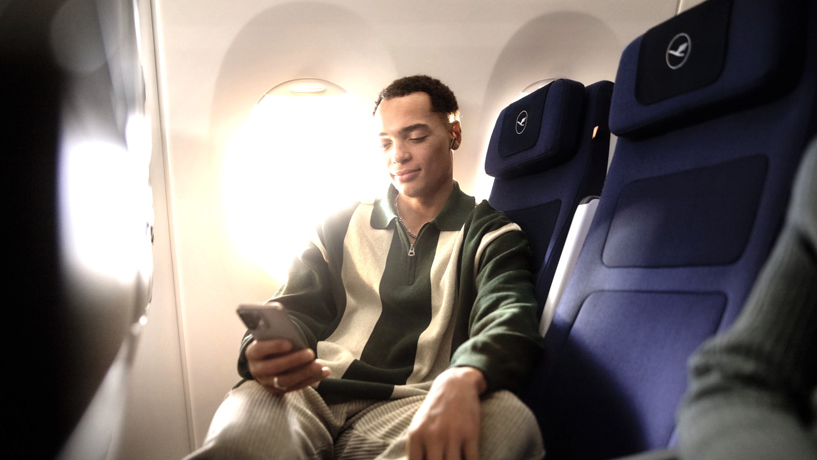 Lufthansa passenger using a phone in an economy cabin