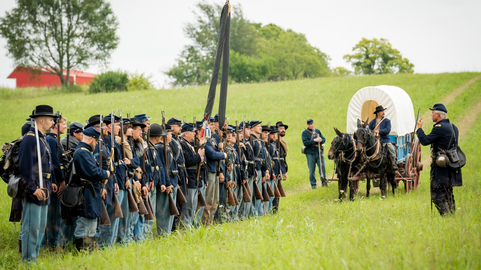 Living historians in Civil War uniforms stand with a mule-drawn wagon at Camp Nelson National Monument