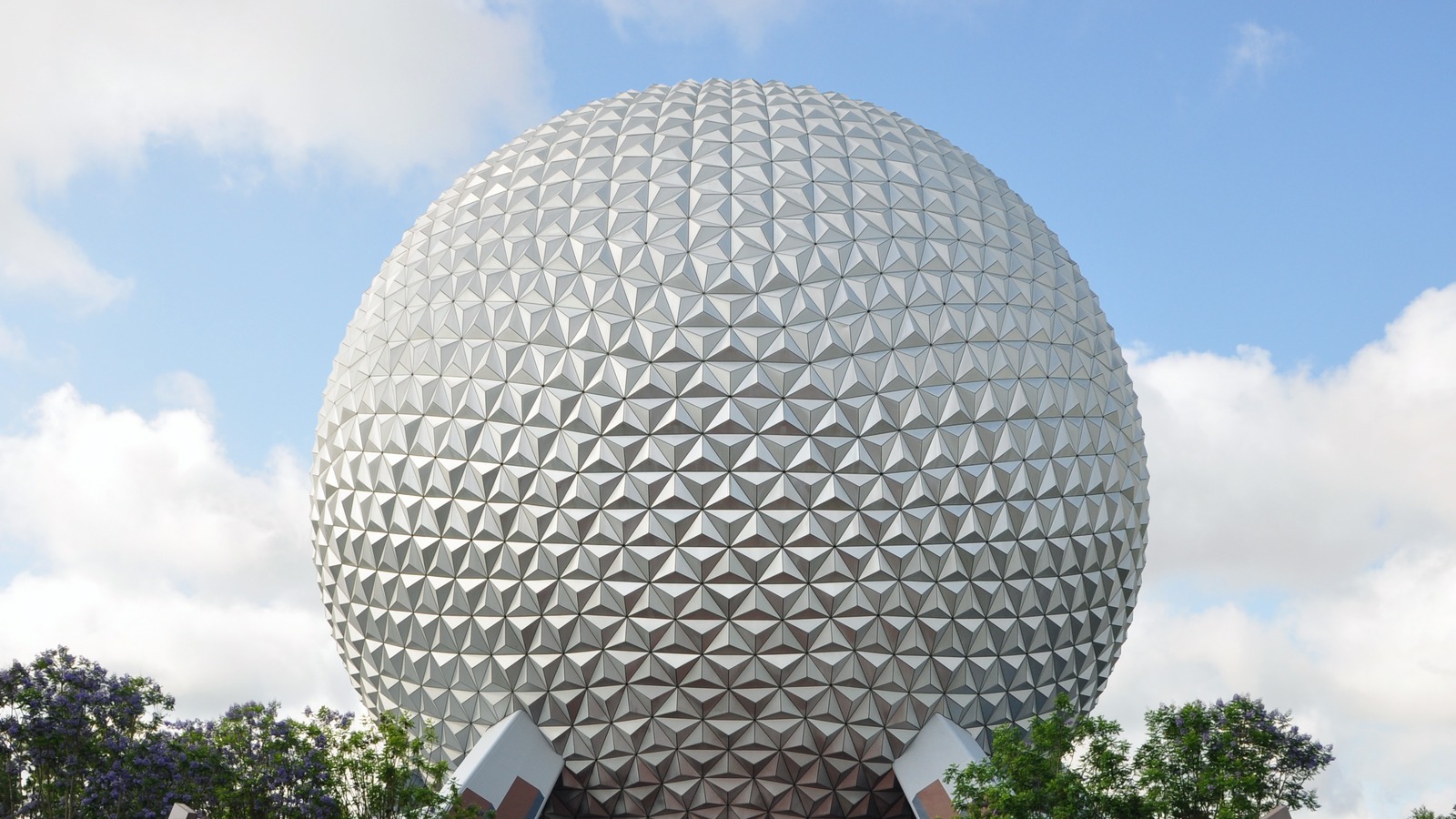 Spaceship Earth geodesic sphere rising above trees at EPCOT under a bright sky