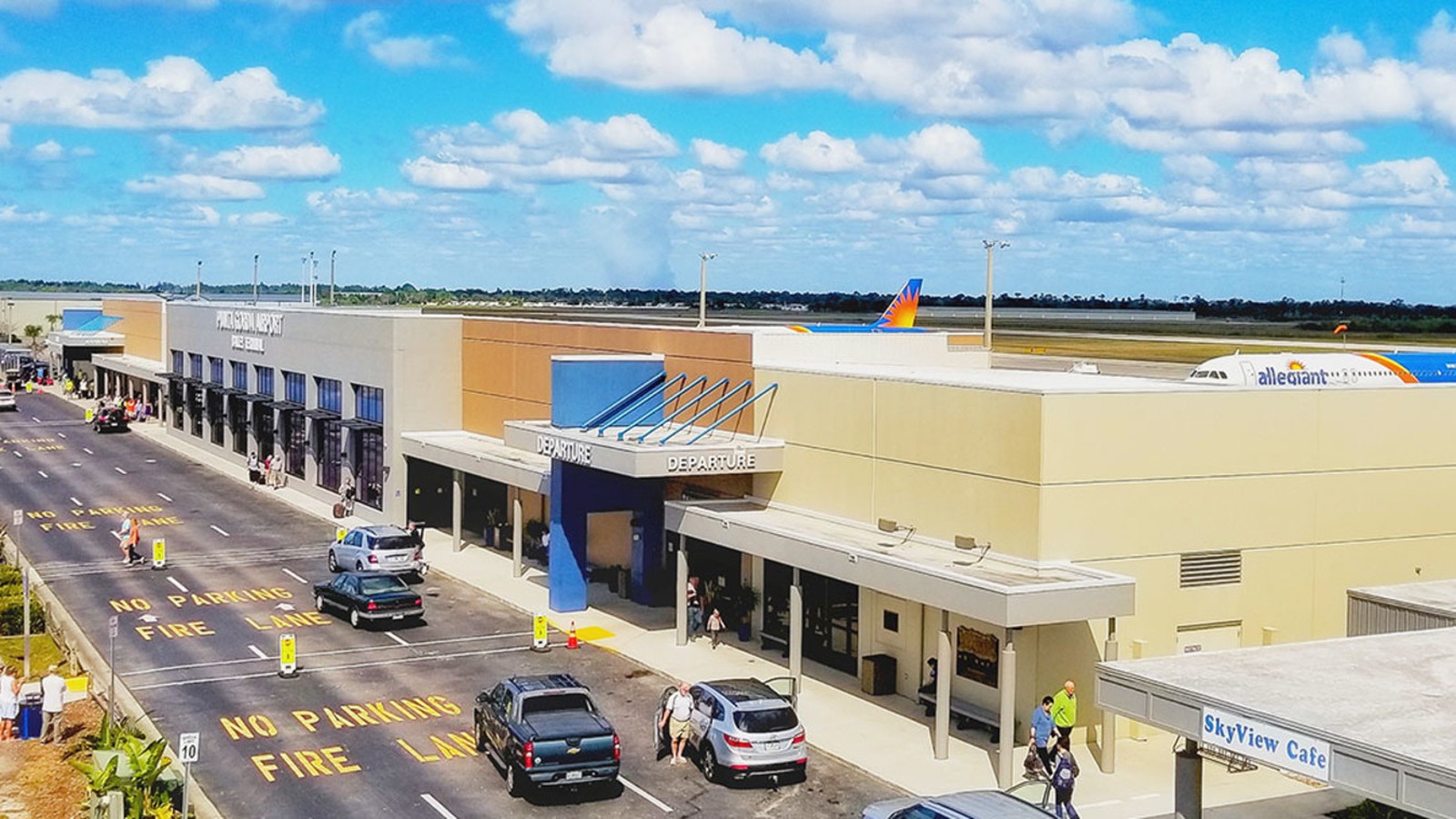 Daylight exterior of Bailey Terminal at Punta Gorda Airport with control tower and aircraft at gate