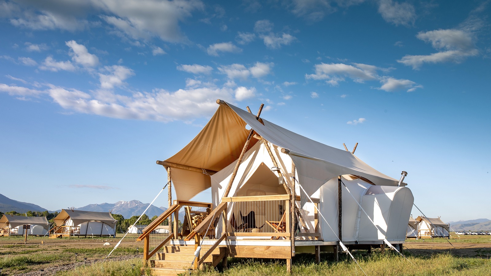 Safari-style Under Canvas tents at dusk with mountain backdrop