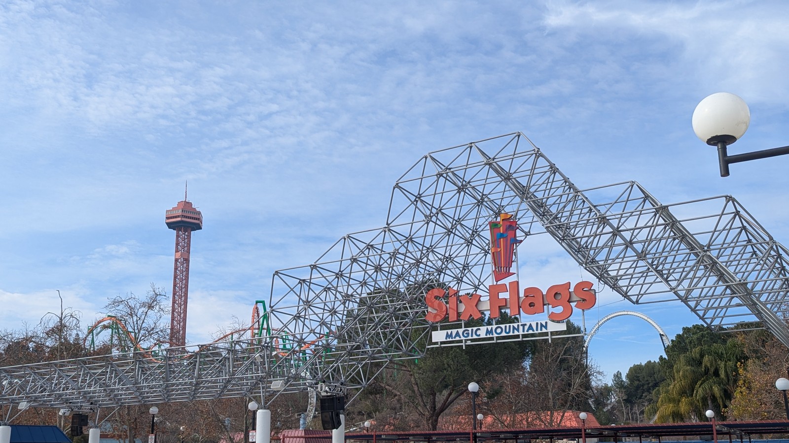Daylight entrance sign reading Six Flags Magic Mountain over an empty plaza