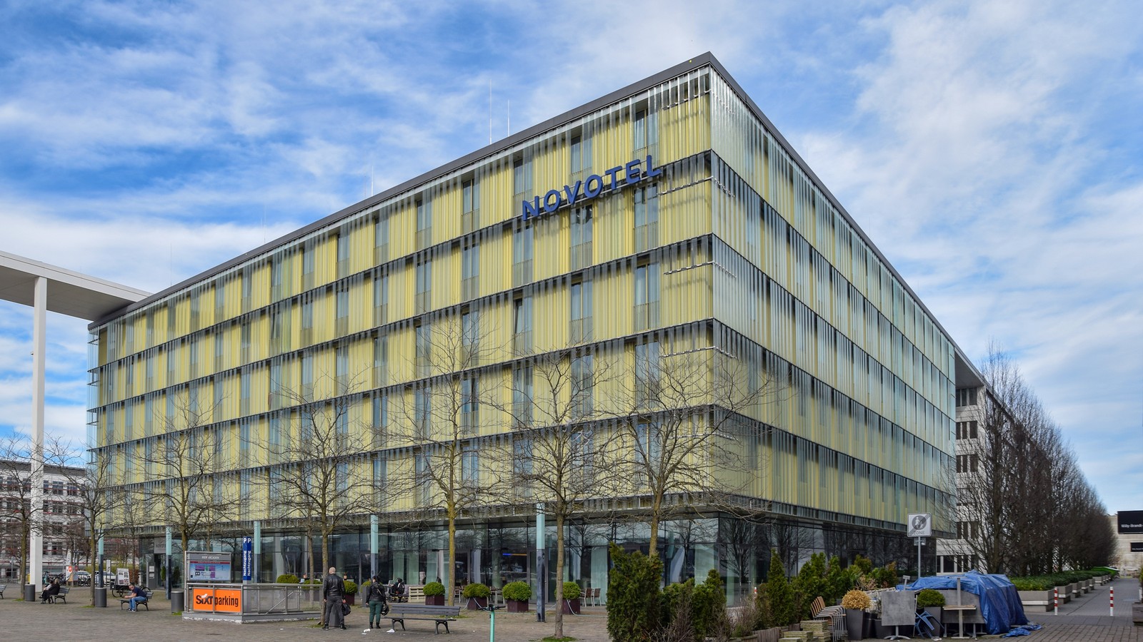 Novotel hotel exterior with blue Novotel signage on a modern glass facade under a bright sky