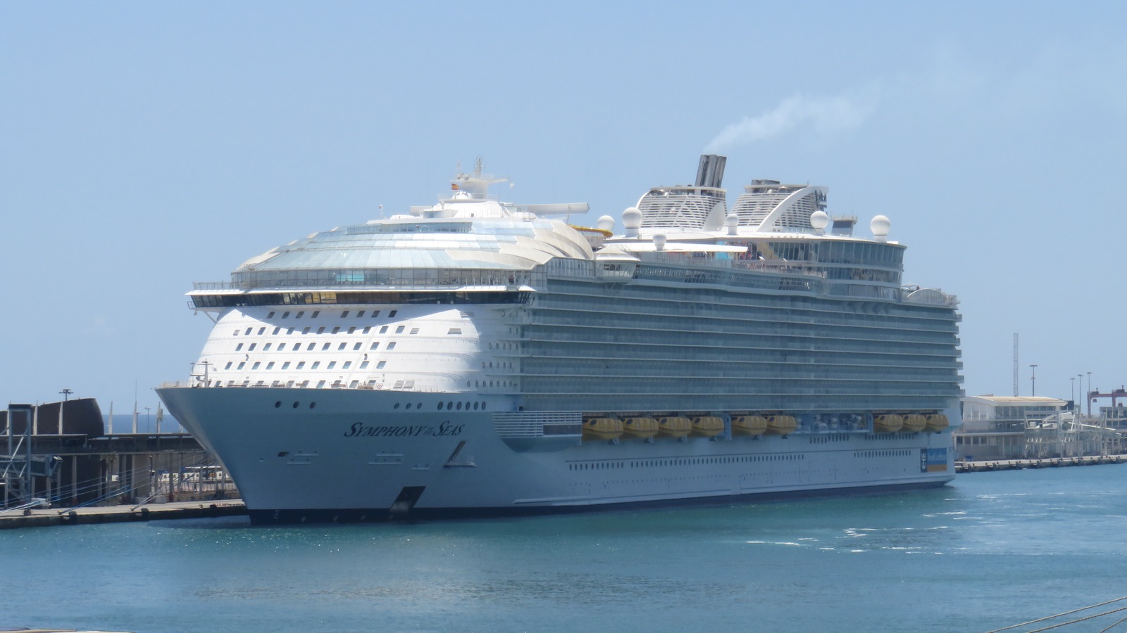 Symphony of the Seas cruise ship with readable hull name at a sunny port